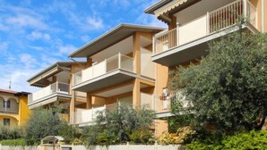 Una hilera de edificios residenciales de varios pisos con balcones, rodeados de vegetación.