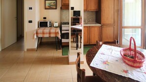 Una cocina compacta con armarios de madera, una mesa de comedor con mantel floral y una cesta roja sobre la mesa.