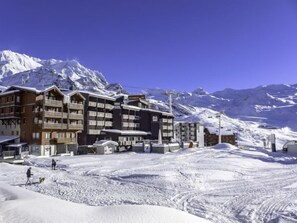 Ein schneebedecktes Bergresort mit mehrstöckigen Gebäuden, Skiliften und blauem Himmel.