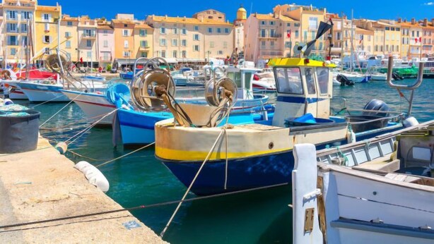 Un puerto deportivo con barcos amarrados, un cielo azul despejado y edificios al fondo.