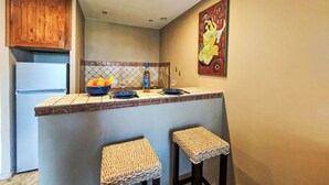 Una cocina con isla central, armarios de madera, salpicadero de azulejos y un cuadro en la pared.