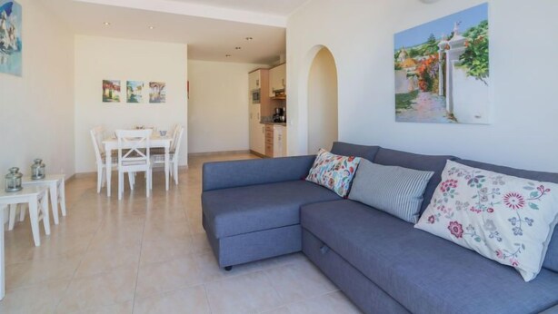 A modern living room with a grey sofa, a dining table with chairs, and a kitchen in the background. - Praia da Luz Sea view by Interhome (Lagos)