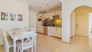 A modern kitchen with white cabinets, a microwave, and a coffee machine. There is a dining table with chairs and a small painting on the wall. - Praia da Luz Sea view by Interhome (Lagos)