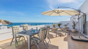 A terrace with a table and chairs, a large umbrella, and a view of the sea. - Praia da Luz Sea view by Interhome (Lagos)