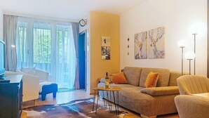 A living room with a sofa, a coffee table, a TV, and a large window with curtains. - FeWo Sun & Snow by Interhome (Bad Hofgastein)