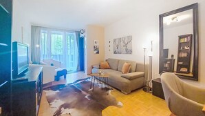 A living room with a sofa, coffee table, and a television. There is a large mirror and a bookshelf. - FeWo Sun & Snow by Interhome (Bad Hofgastein)