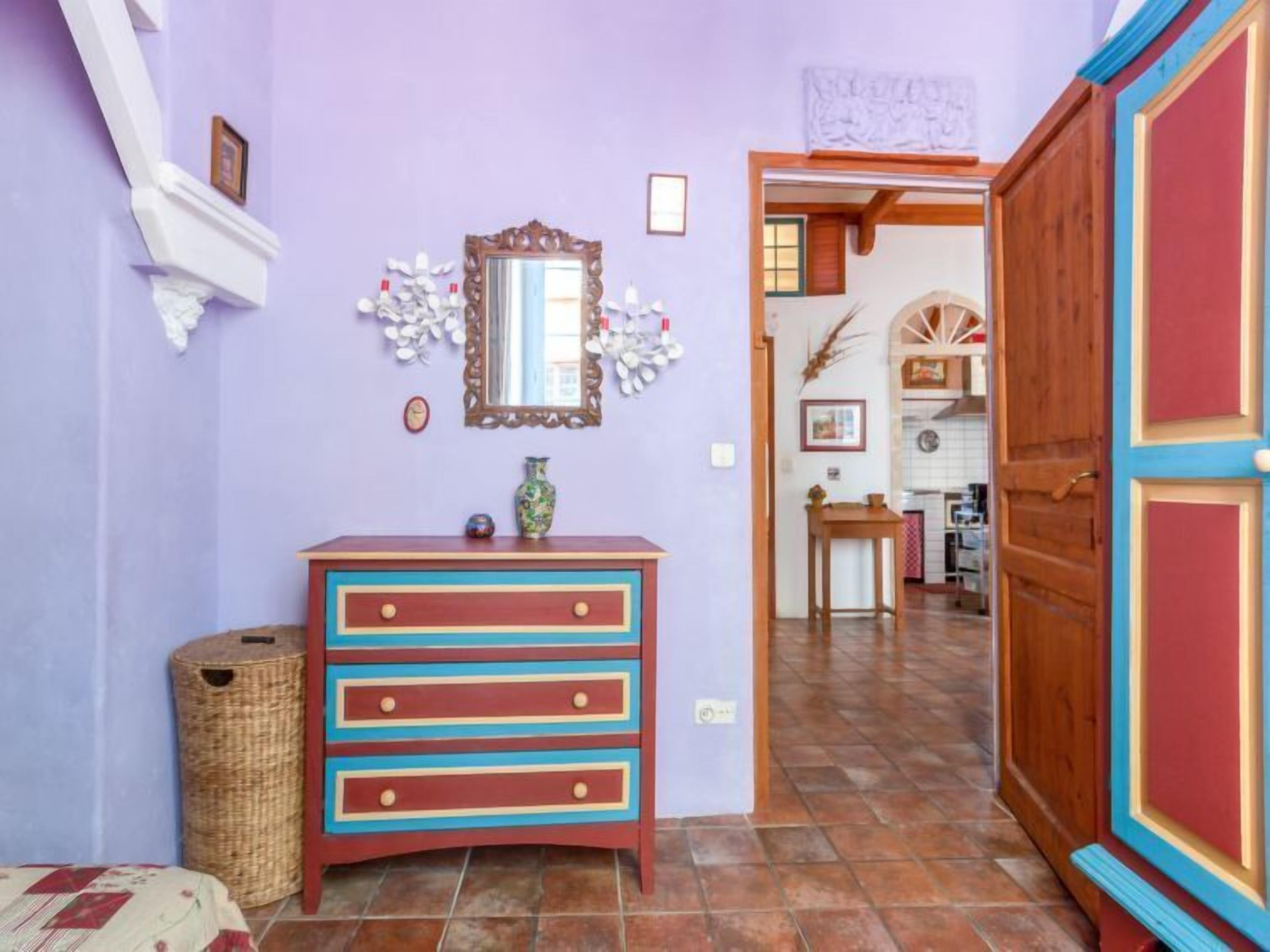 Een kamer met een houten dressoir, een spiegel en een rieten mand.