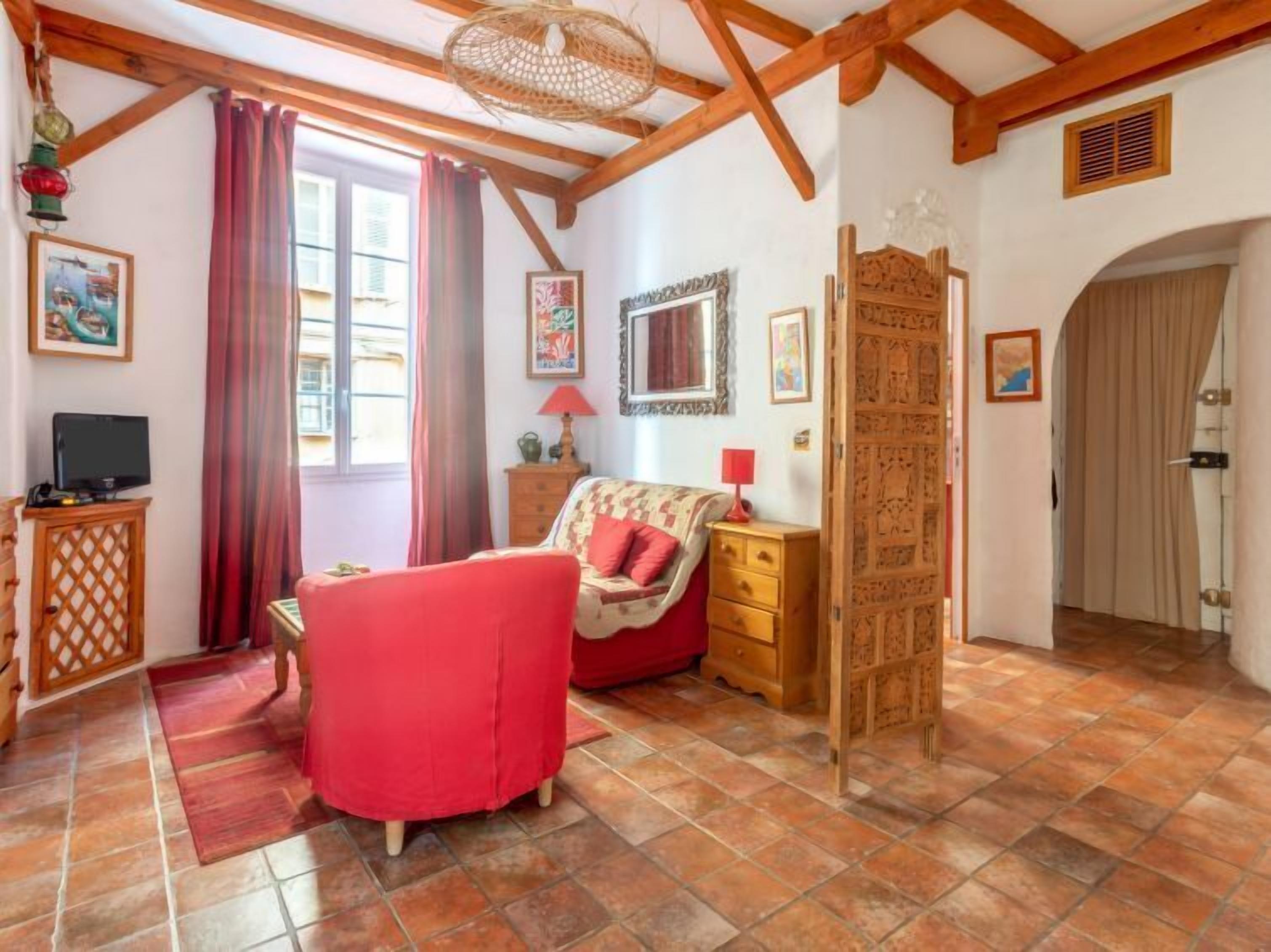 A cozy room with a red sofa, wooden furniture, and a large window with curtains.