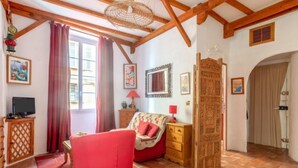 Ein gemütliches Zimmer mit einem roten Sofa, Holzmöbeln und einem großen Fenster mit Vorhängen.