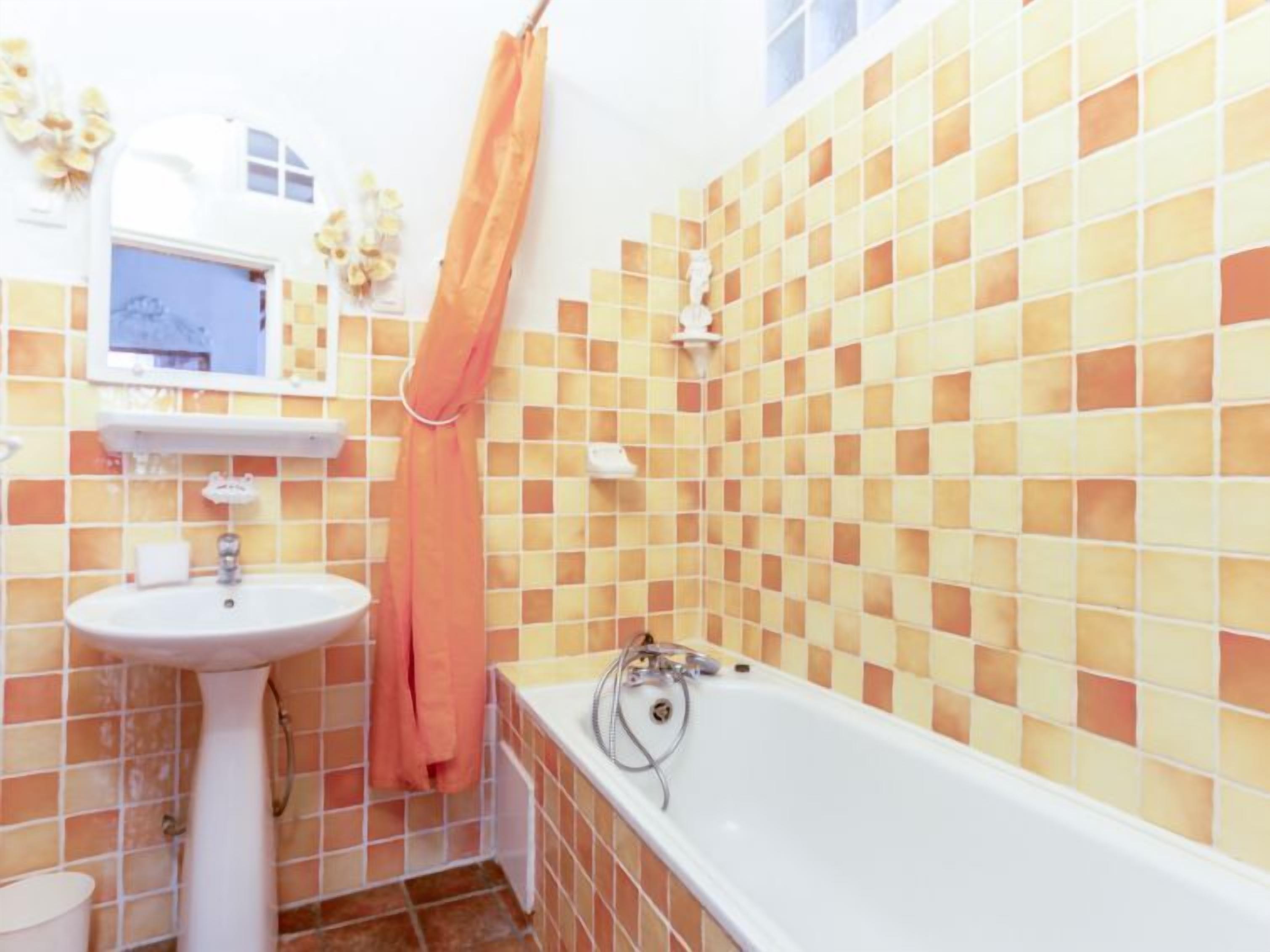A bathroom with a sink, mirror, and bathtub.