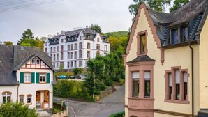 A street with traditional European architecture, including a building with a steeply pitched roof and a building with a bay window.