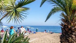 Una spiaggia con palme, ombrelloni e persone che si rilassano.