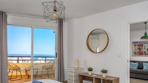 Una camera da letto con un letto grande, vista mare, un balcone con sedie e un tavolino consolle in legno.