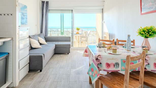 A modern, well-lit room with a sofa, dining table, and a view of the beach. - les Goelands by Interhome (Mimizan)