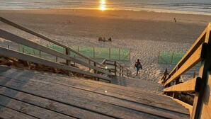 A wooden staircase leading down to a beach with a sunset in the background. - les Goelands by Interhome (Mimizan)