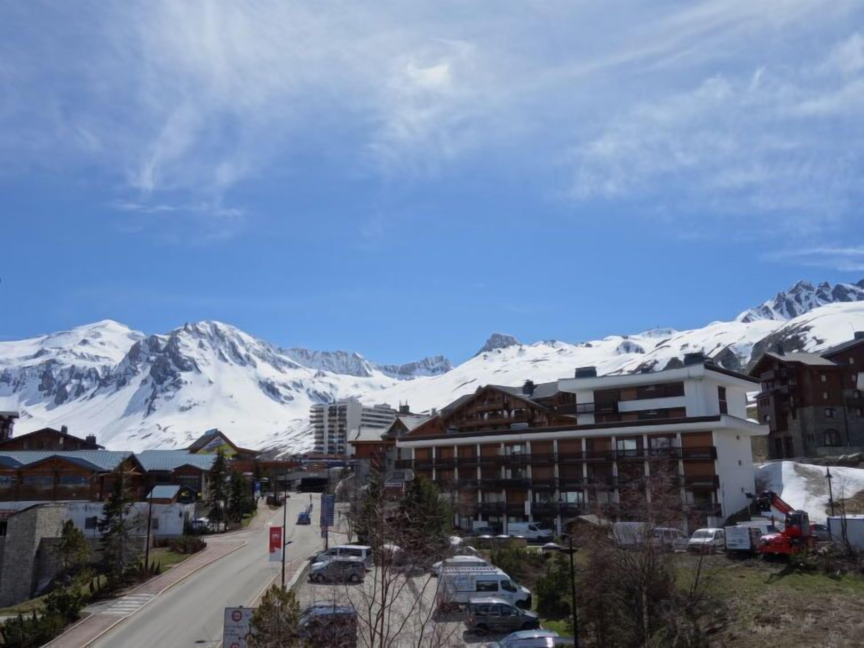 Ein Bergresort mit schneebedeckten Gipfeln im Hintergrund, modernen Gebäuden und einer Straße im Vordergrund.
