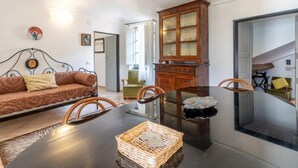 A dining area with a glass-top table, a wooden cabinet with glass doors, a brown sofa, and a green armchair. - Canneto by Interhome (Marina di Andora)