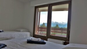A hotel room with a bed, a window with a view of mountains, and a balcony. - Monte Cristo 6 by Interhome (Crans-Montana)
