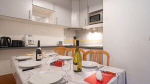 A dining area with a table set for four, white cabinets, a microwave, and a coffee maker. - Balcons d'Olympie 305 - A by Interhome (Les Menuires)