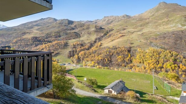 A balcony overlooking a mountainous landscape with autumn foliage, a small house, and a clear sky. - Balcons d'Olympie 305 - A by Interhome (Les Menuires)