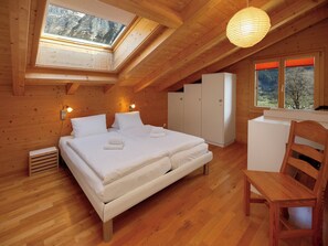 Une cabane en bois avec une chambre à coucher située en mezzanine, un lit, un bureau et une chaise.
