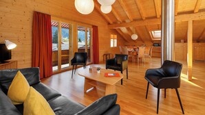 A wooden interior with a sofa, chairs, a dining table, and a kitchen area. - Chalet Almisgässli by Interhome (Grindelwald)