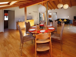 Uma sala de jantar com uma mesa de madeira posta para quatro pessoas, rodeada por cadeiras.