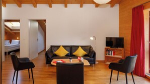 A modern living room with a sofa, two chairs, a coffee table, a TV, and a bookshelf. - Chalet Almisgässli by Interhome (Grindelwald)
