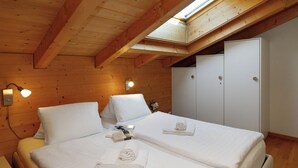 A room with two beds, wooden walls, a skylight, and a wardrobe. - Chalet Almisgässli by Interhome (Grindelwald)