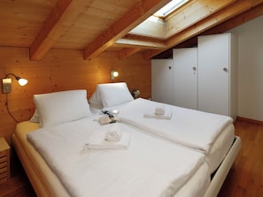 A room with two beds, wooden walls, a skylight, and a wardrobe.
