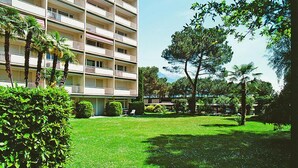 A multi-story hotel with balconies, a well-maintained lawn, and surrounding greenery.