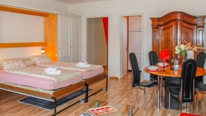 A bedroom with a bed, a desk, and a dining area.