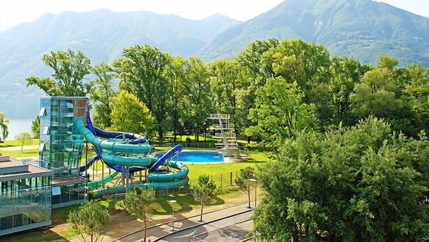 A water park with slides and a pool, surrounded by trees and mountains.