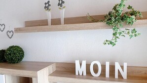Uma prateleira de madeira com uma planta e flores decorativas.
