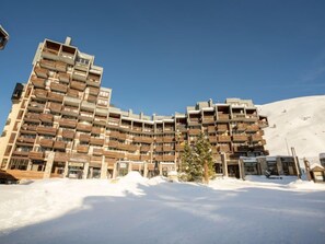 A multi-story hotel with balconies, a ski slope in the background, and a snowy landscape. - Le Curling A (Val Claret) by Interhome (Tignes)