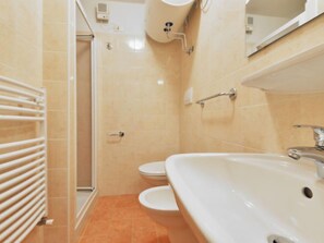 A bathroom with a white sink, toilet, and shower.