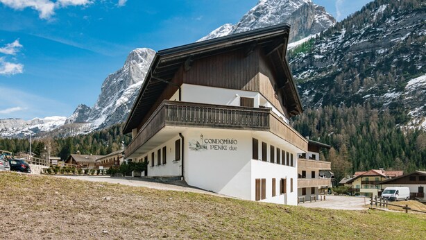 A mountain lodge with a wooden facade and a balcony, surrounded by snow-capped mountains and clear skies. - Penia 2 by Interhome (Canazei)