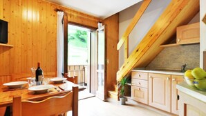 A wooden interior with a dining area, kitchen, and a view through a glass door. - Penia 2 by Interhome (Canazei)