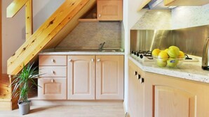 A kitchen with wooden cabinets, a gas stove, and a sink. - Penia 2 by Interhome (Canazei)