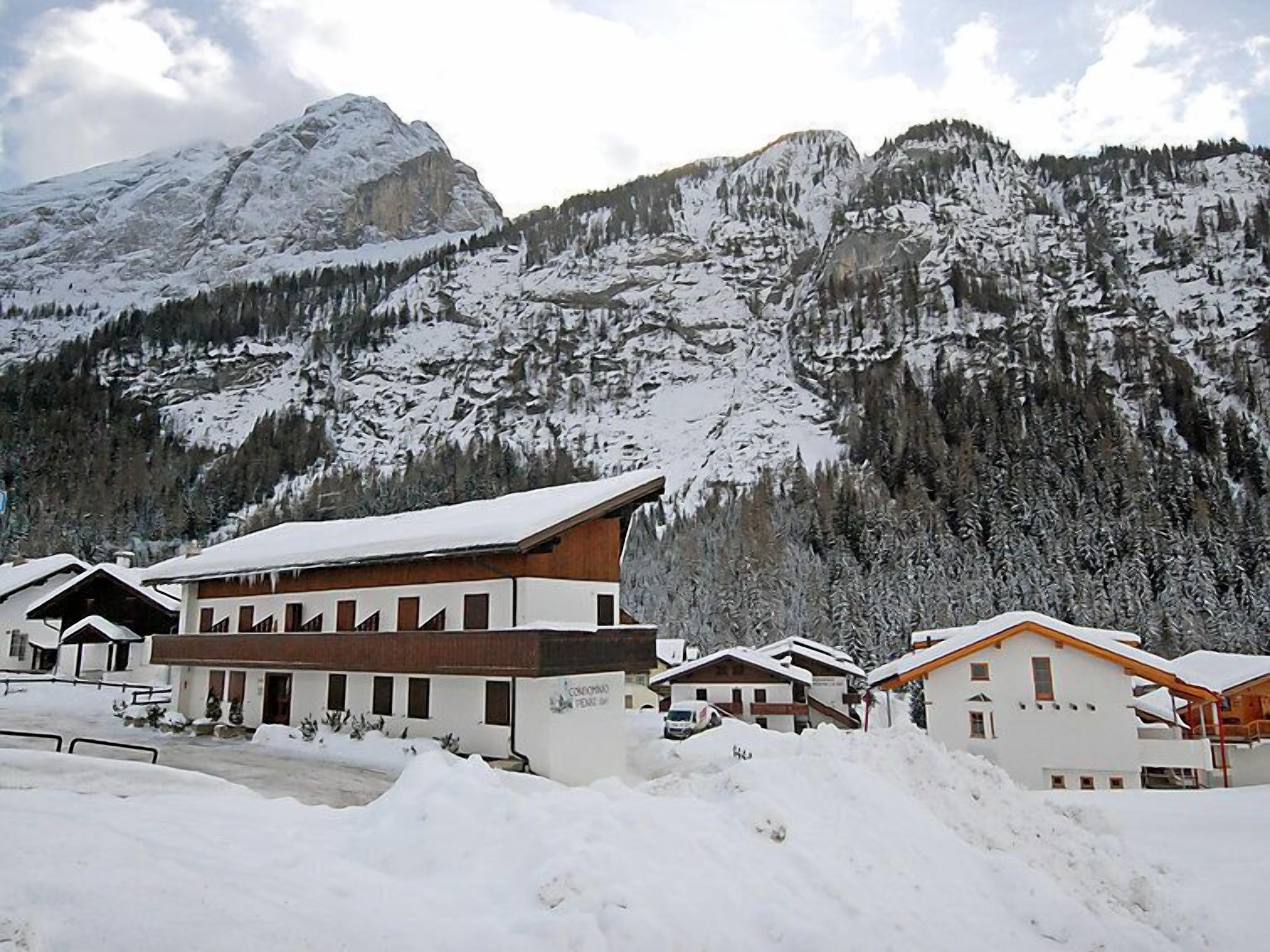 A snow-covered mountain with a chalet-style building in the foreground.