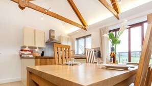 A modern kitchen with wooden beams, a dining table, and a view of the outdoors. - Villa Gallery by Interhome (Truro)
