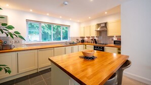 A modern kitchen with a central island, a window with blinds, and a stove. - Villa Gallery by Interhome (Truro)