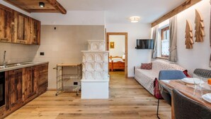 Une chambre d’hôtel compacte dotée d’une kitchenette, d’un plancher en bois, d’un lit avec télévision et d’un coin repas.