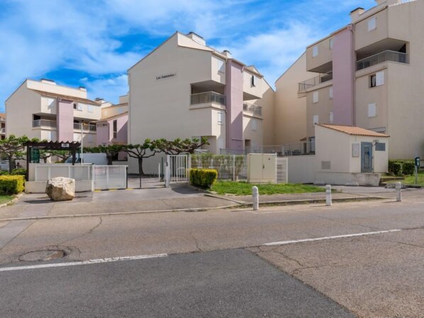 A residential building with multiple balconies and a gated entrance.