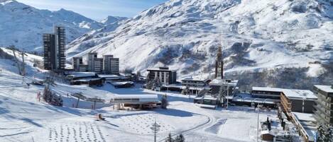 Una località sciistica innevata con edifici moderni, impianti di risalita e uno sfondo montuoso.
