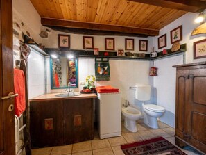 Een landelijke keuken met houten balken, een gootsteen, toilet en een kast.