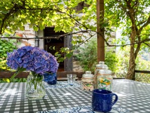Een geruit tafereel met een vaas paarse bloemen, glazen potten en een blauwe mok.