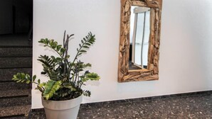 A potted plant with green leaves and a wooden-framed mirror on a white wall. - Alpenland by Interhome (Seefeld in Tirol)