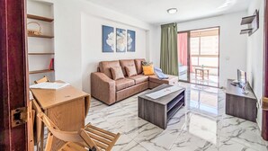 Ein Wohnzimmer mit einer Couch, einem Holztisch, einem Couchtisch und Blick ins Freie.