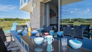 Un coin repas avec une table dressée pour deux personnes, un mur en pierre et une vue sur la campagne.